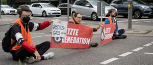 Drei Klimaaktivisten der Gruppe «Aufstand der letzten Generation» blockieren eine Straße in Stuttgart. 