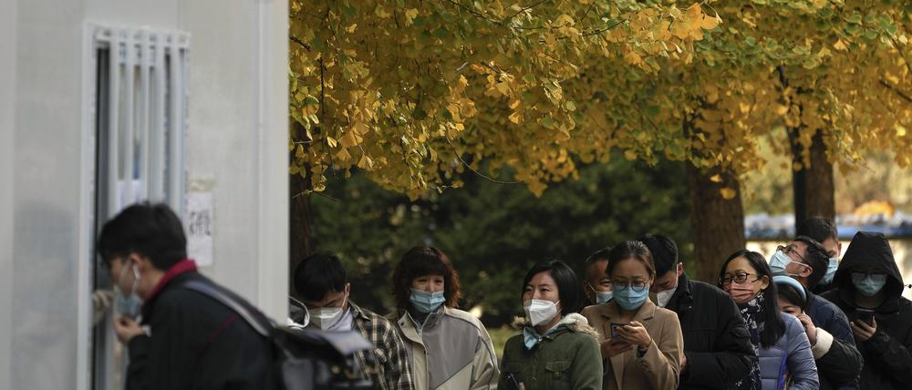 08.11.2022, China, Peking: Menschen mit Gesichtsmasken stehen an, um ihre routinemäßigen COVID-19-Rachenabstriche in einem Coronavirus-Testzentrum in Peking zu erhalten.