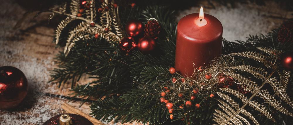 Adventskranz-Kerze und Holz-Aufschrift: Frohe Weihnachten.