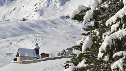 Eine Kirche steht in einer verschneiten Berglandschaft.