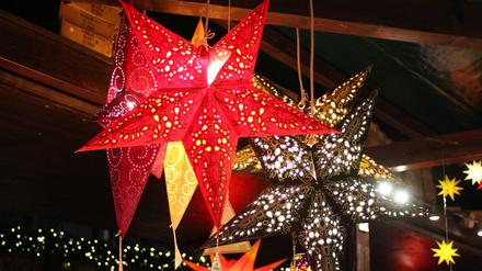 Weihnachtssterne, die beleuchtet sind, hängen unter einem Holzdach.