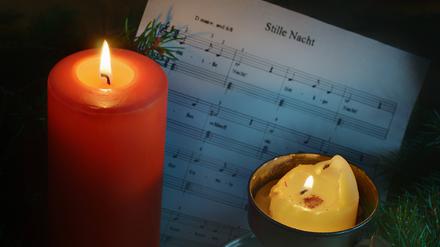 Leuchtende Weihnachtskerzen vor Weihnachtsnoten.
