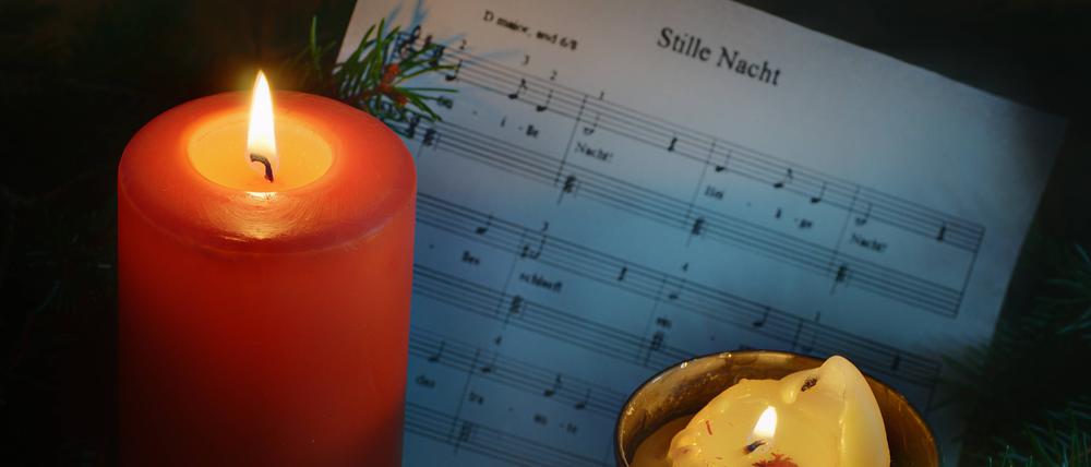 Leuchtende Weihnachtskerzen vor Weihnachtsnoten.
