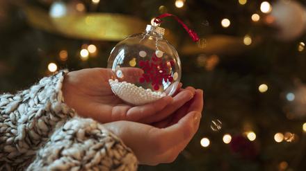 Eine Frau hält eine kleine Christbaumkugel in den Händen. 