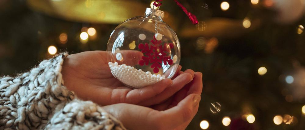 Eine Frau hält eine kleine Christbaumkugel in den Händen.