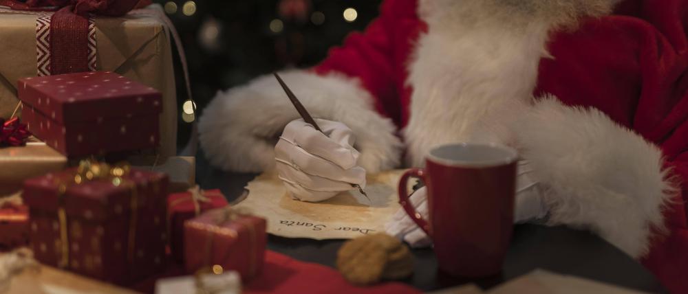 Der Weihnachtsmann schreibt neben Geschenken einen Brief.