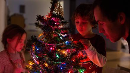 Eine Familie dekoriert den Weihnachtsbaum.