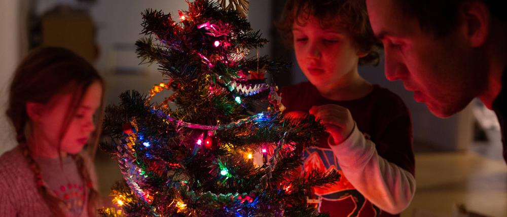 Eine Familie dekoriert den Weihnachtsbaum.