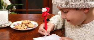 Ein Kind schreibt einen Weihnachtswunsch auf einen Zettel.