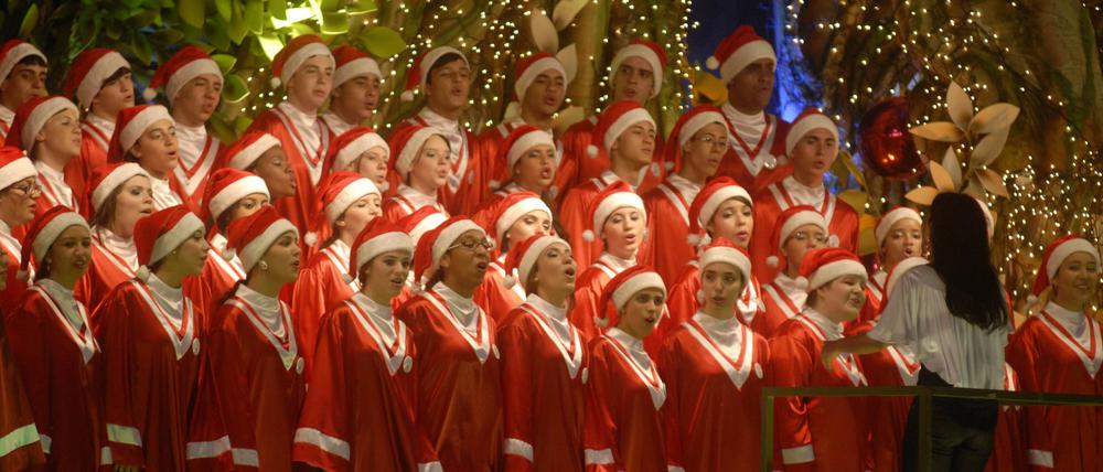 Ein Weihnachtschor singt in Weihnachtsmannkostümen. 