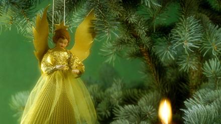 Ein Weihnachtsengel hängt an einem Tannenbaum.