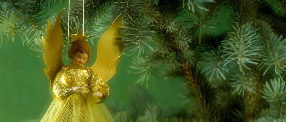 Ein Weihnachtsengel hängt an einem Tannenbaum.