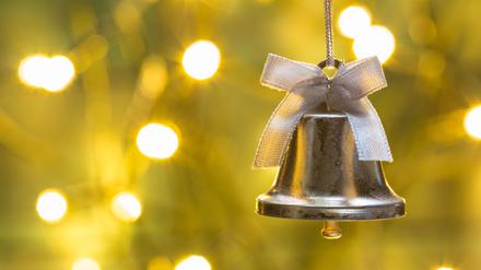 Eine Weihnachtsglocke hängt vor einem beleuchteten Hintergrund.