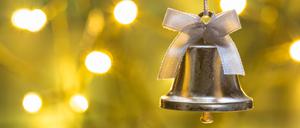 Eine Weihnachtsglocke hängt vor einem beleuchteten Hintergrund.