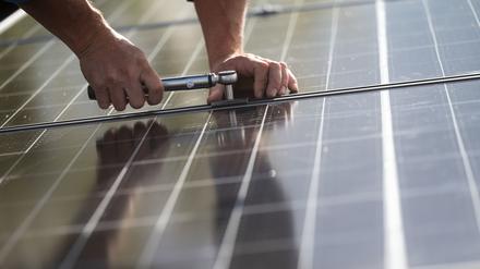 Mitarbeiter der Firma Sontec GmbH montieren Photovoltaikmodule auf dem Dach eines Wohnhauses.