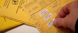 Eine Arzthelferin klebt in einer Praxis den Nachweis einer Impfung mit einem Corona-Impfstoff in ein Impfbuch (Symbolbild)