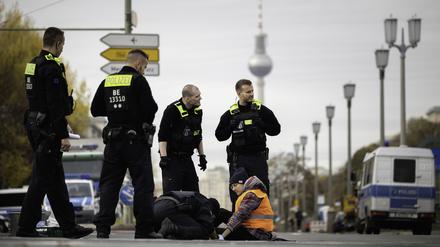 Polizisten lösen eine Aktivistin der Gruppe „Letzte Generation“ von der Kreuzung Frankfurter Tor, die sich bei einer Sitzblockade mit einer Hand am Asphalt festgeklebt hat. 