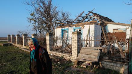 Eine Frau vor einem schwer beschädigten Haus in der Region Cherson