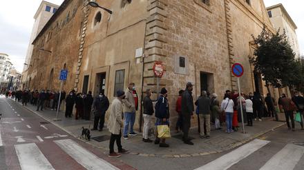 Menschen in Palma de Mallorca warten in einer Schlange, um ein Wohltätigkeits-Weihnachtsessen für arme und obdachlose Menschen in der Caputxins-Kirche zu bekommen.