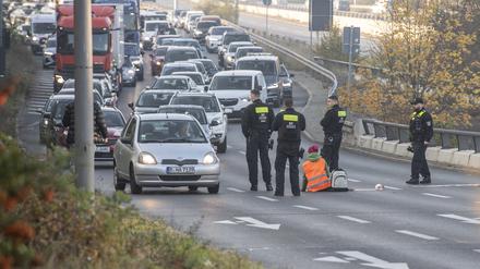 Eine Demonstrantin der Gruppe „Letzte Generation“ sitzt, umringt von Polizeibeamten, auf der Ausfahrt der Stadtautobahn am Sachsenring. Foto: Paul Zinken/dpa