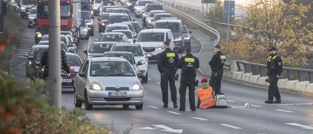 Eine Demonstrantin der Gruppe „Letzte Generation“ sitzt, umringt von Polizeibeamten, auf der Ausfahrt der Stadtautobahn am Sachsenring. Foto: Paul Zinken/dpa