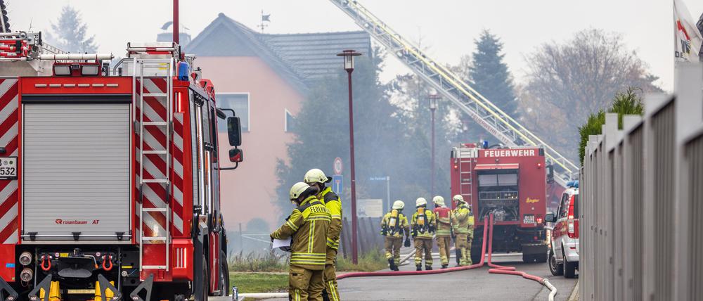 18.11.2022, Brandenburg, Cottbus: Feuerwehrkräfte sind mit Löscharbeiten an einem Einfamilienhaus beschäftigt. Ein am frühen Morgen in einem Carport im Cottbuser Ortsteil Branitz ausgebrochener Brand griff auf einen Kostümverleih über. Wegen der entstehenden Rauchentwicklung war die Bevölkerung gewarnt worden Foto: Frank Hammerschmidt/dpa +++ dpa-Bildfunk +++