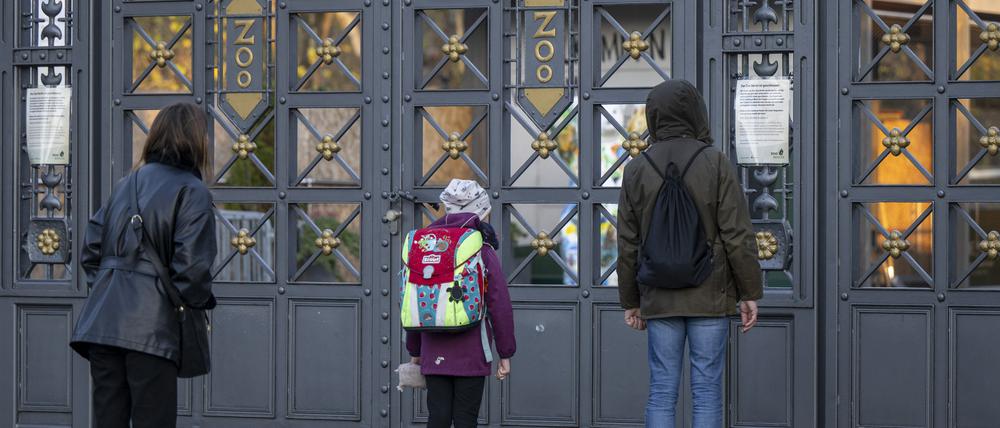 Besucher stehen am Nachmittag vor einem geschlossenen Tor am Eingang zum Berliner Zoo.