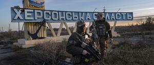 Zwei Mitglieder der ukrainischen Verteidigungskräfte stehen neben einem Schild mit der Aufschrift „Region Cherson“ am Stadtrand. 