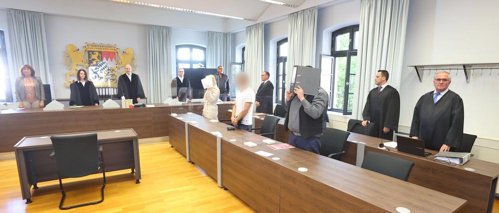 Eine Jugendliche (l) und ein Erwachsener (r) stehen in einem Gerichtssaal des Landgerichtes in Memmingen in der Anklagebank.