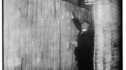 Ein Angestellter zählt 1923 Geldscheinstapel in einer Berliner Bank.