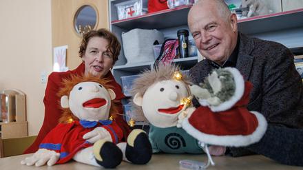 Elke Büdenbender, Ehefrau des Bundespräsidenten, und Matthias Bräutigam (r), Sprachpate, spielen mit Handpuppen bei dem Besuch einer Kita in einem Kinderzimmer.