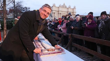 Potsdams Oberbürgermeister Mike Schubert (SPD) schneidet auf dem Weihnachtsmarkt den Riesenstollen an.