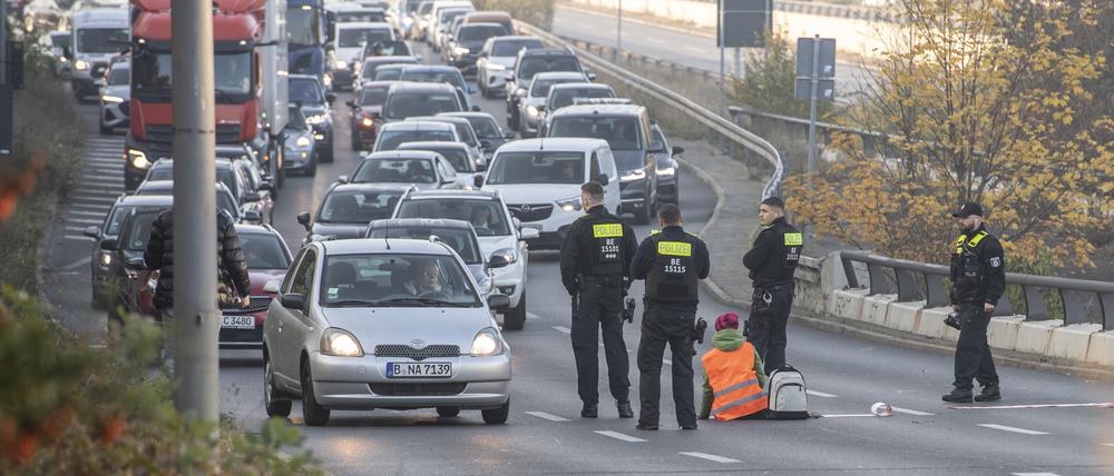 Eine Demonstrantin der Gruppe „Letzte Generation“ sitzt, umringt von Polizeibeamten, auf der Ausfahrt der Stadtautobahn am Sachsenring.