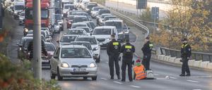 Eine Demonstrantin der Gruppe „Letzte Generation“ sitzt, umringt von Polizeibeamten, auf der Ausfahrt der Stadtautobahn am Sachsenring.