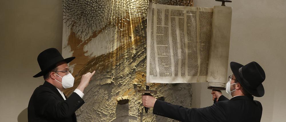 Rabbiner Elias Dray (l) schaut zu Rabbiner Shaul Nekrich, der die historische Sulzbacher Torarolle von 1792 hochhält, nachdem er sie während einer Zeremonie zum 76. Jahrestag der Befreiung des deutschen Vernichtungslagers Auschwitz am Internationalen Holocaust-Gedenktag in einem Andachtsraum auf dem Gelände des Bundestags vervollständigt hat.