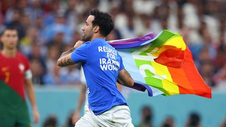 Ein Flitzer mit der Regenbogenflagge und politischen Botschaften zur Ukraine und Iran auf dem T-Shirt läuft über den Rasen.