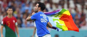 Ein Flitzer mit der Regenbogenflagge und politischen Botschaften zur Ukraine und Iran auf dem T-Shirt läuft über den Rasen.
