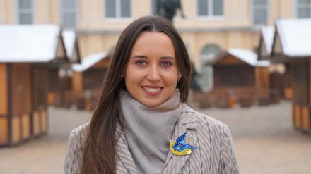 Iryna Bushmina aus Kiew assistiert dem Veranstalter des Berliner Weihnachtsmarkts vor dem Schloss Charlottenburg.