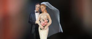 Ein Hochzeitspaar aus Wachs steht auf einer Hochzeitstorte.