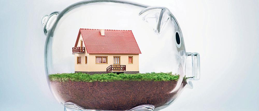 Saving to buy a house or home savings concept with model house inside transparent piggy bank. Viele Deutsche haben vor Jahren aus heutiger Sicht hochverzinste Bausparverträge abgeschlossen. Foto: POGONICI - FOTOLIA