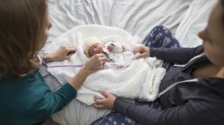 Zu Besuch beim neuen Erdenbürger: Eine Hebamme und eine Mutter mit ihrem Kind.