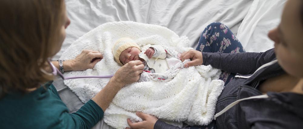 Zu Besuch beim neuen Erdenbürger: Eine Hebamme und eine Mutter mit ihrem Kind.