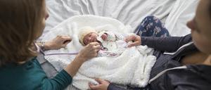 Zu Besuch beim neuen Erdenbürger: Eine Hebamme und eine Mutter mit ihrem Kind.