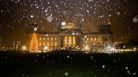 Schneeflocken fallen vor dem Reichstagsgebäude. 