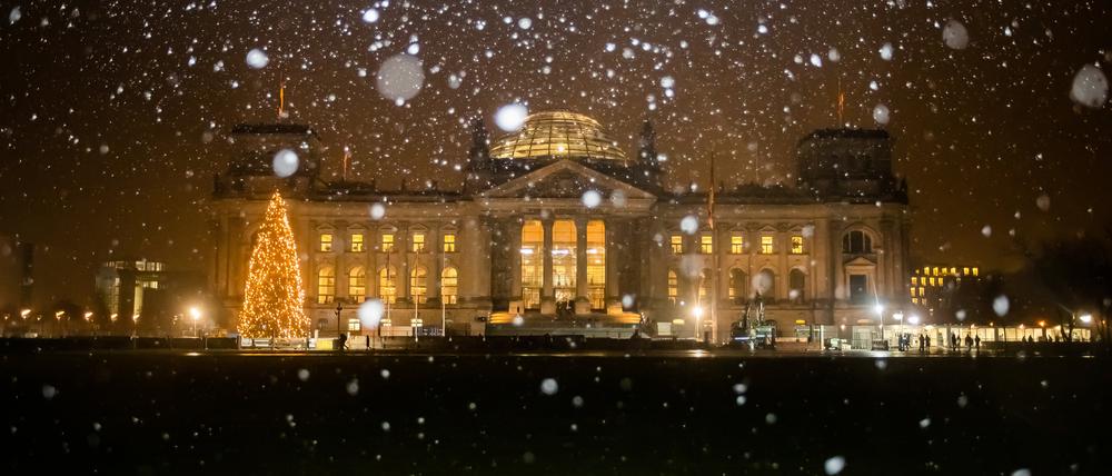 Schneeflocken fallen vor dem Reichstagsgebäude.