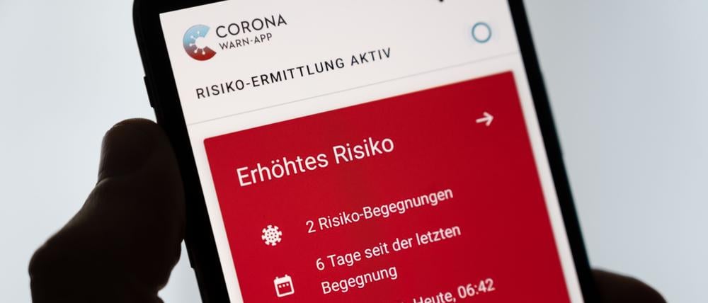 ILLUSTRATION - Ein Mann hÃ¤lt ein Smartphone in der Hand, auf dem die Corona-Warn-App der Bundesregierung ein erhÃ¶htes Risiko anzeigt (gestellte Szene).
