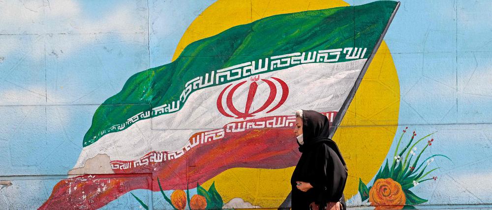 Eine Frau läuft an einer Mauer in Teheran vorbei.