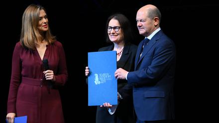 Bundeskanzler Olaf Scholz (r-l, SPD) überreicht Irina Scherbakowa, Mitgründerin der russischen Menschenrechtsorganisation Memorial, den Marion-Dönhoff-Preis neben Moderatorin Julia-Niharika Sen auf der Bühne im Deutschen Schauspielhaus.