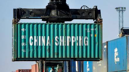 Ein Mann rangiert Container für die Weiterverladung in einer Logistikstation. 