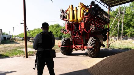 Ein landwirtschaftlicher Traktor wird von einem bewaffneten Security bewacht (Symbolbild)